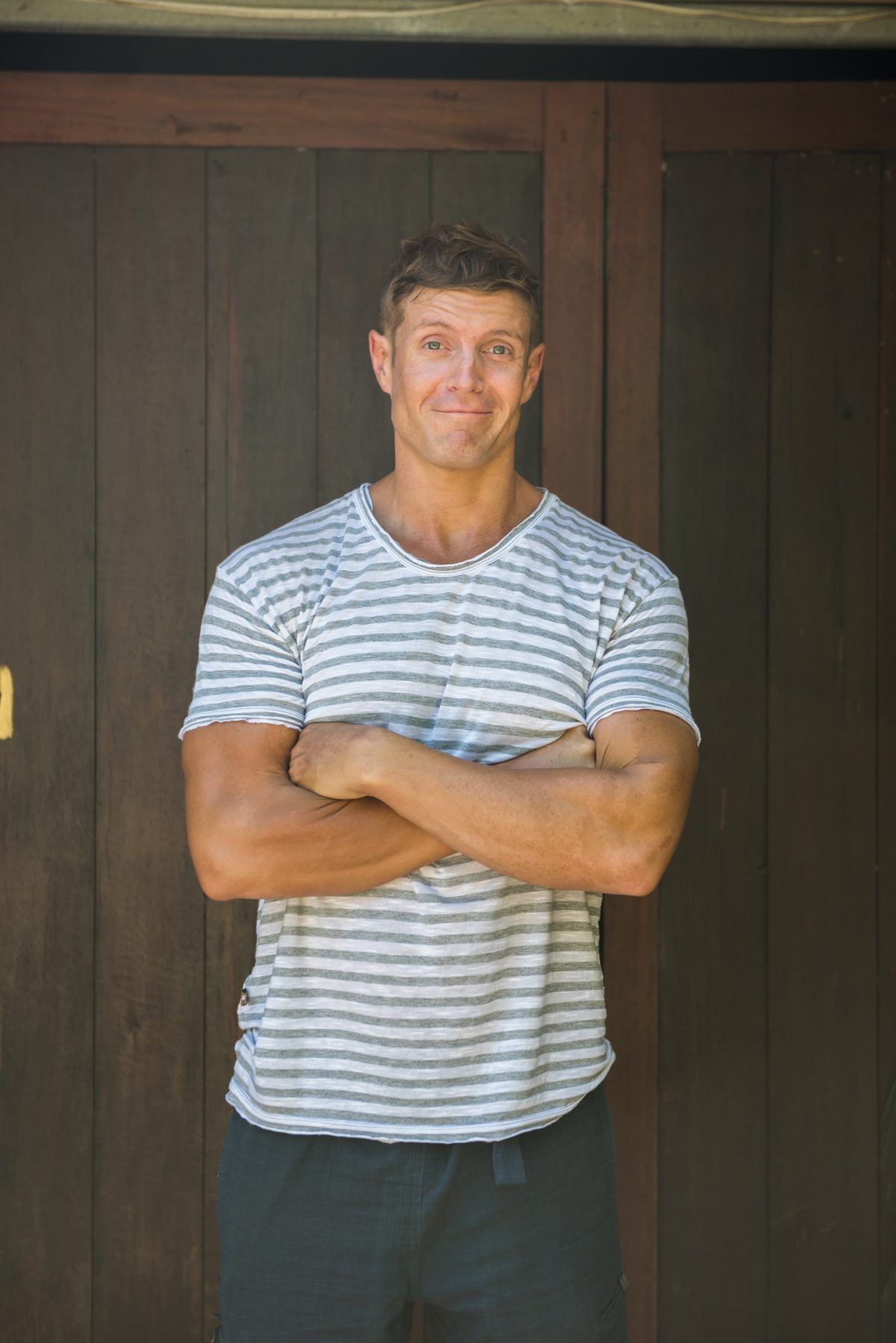 Dai Manuel standing with his arms crossed against a timber wall