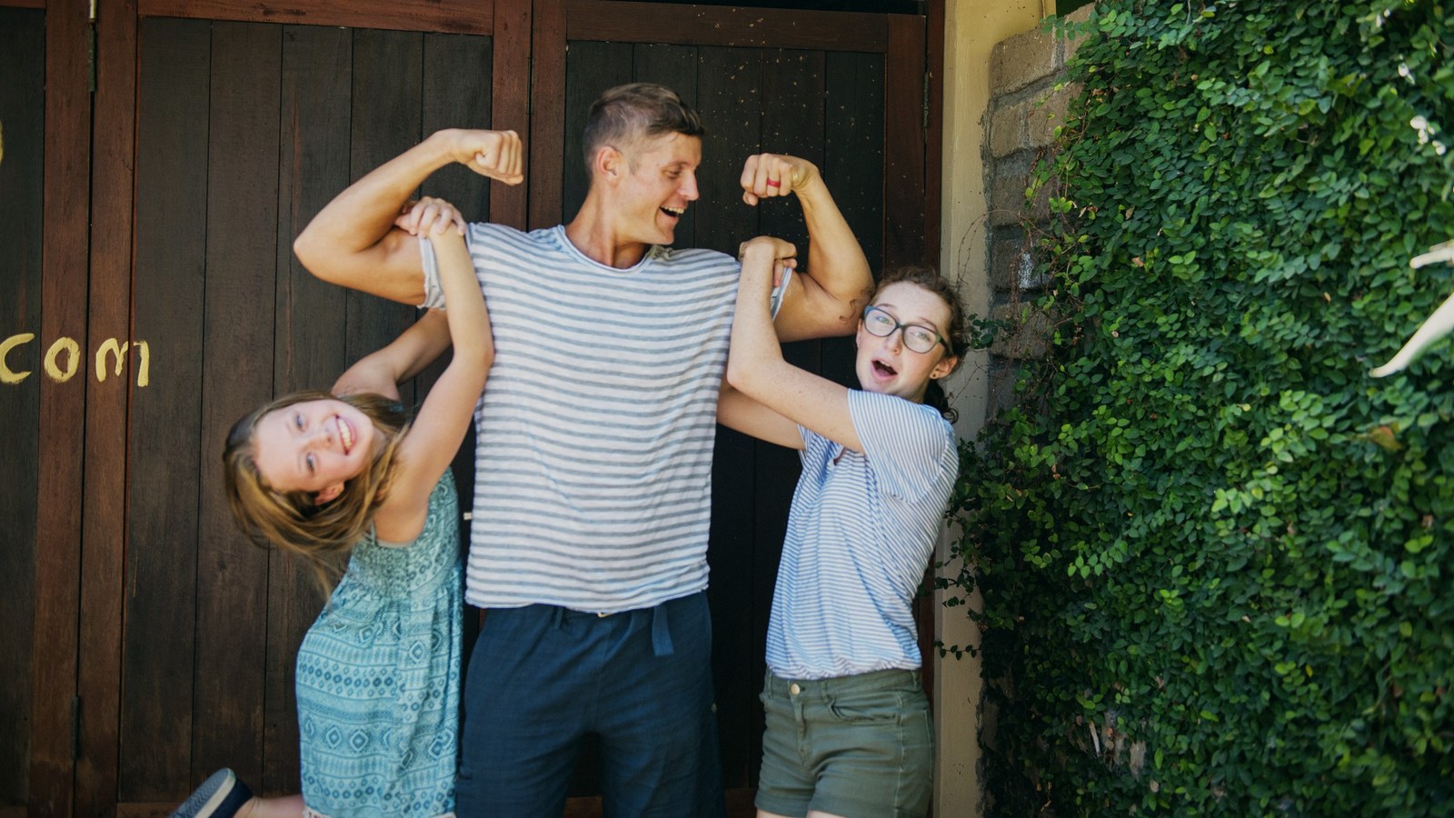 Dai Manuel flexing between his two daughters, all three laughing